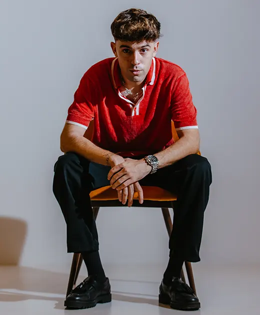 Raude con un polo rojo sentado en una silla